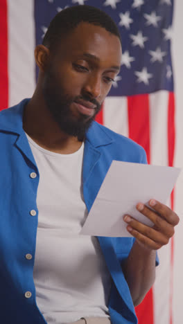 Vertical-Video-Shot-Of-Man-Next-To-Booth-With-Ballot-Paper-In-American-Election-Deciding-How-To-Cast-His-Vote-4